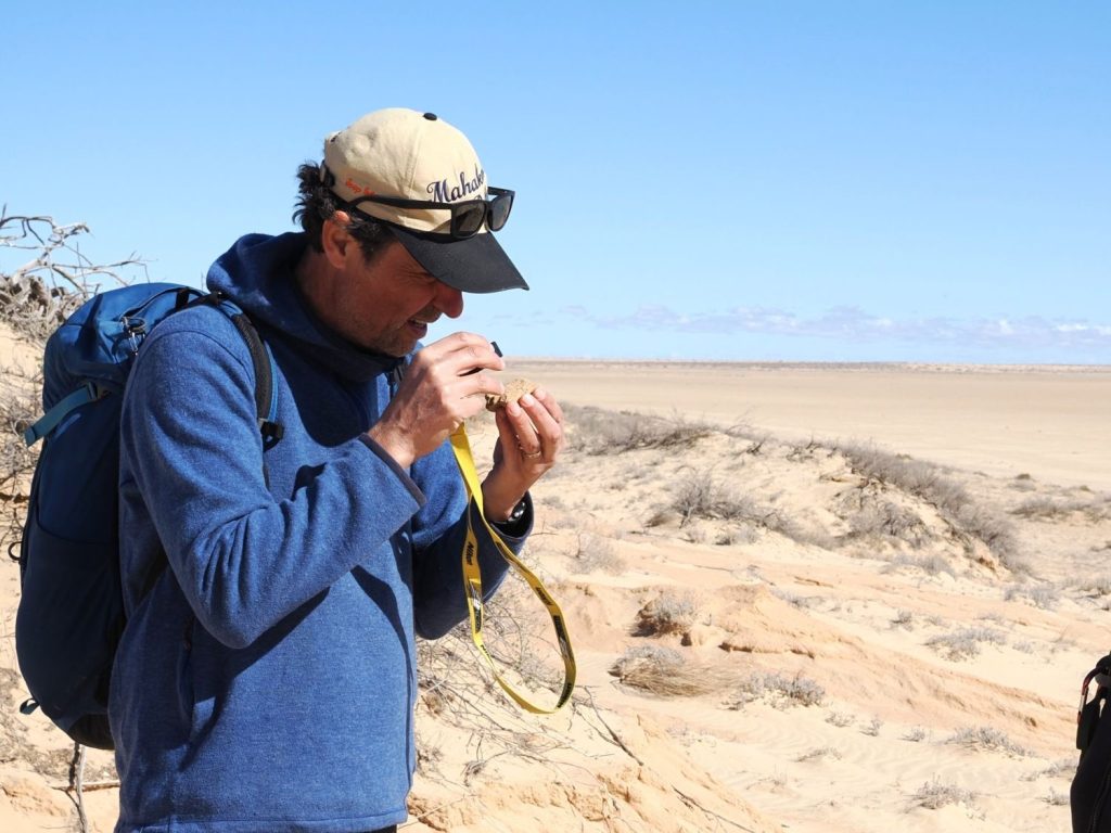 Joep Storms bekijkt een stuk zout of sediment met een loep